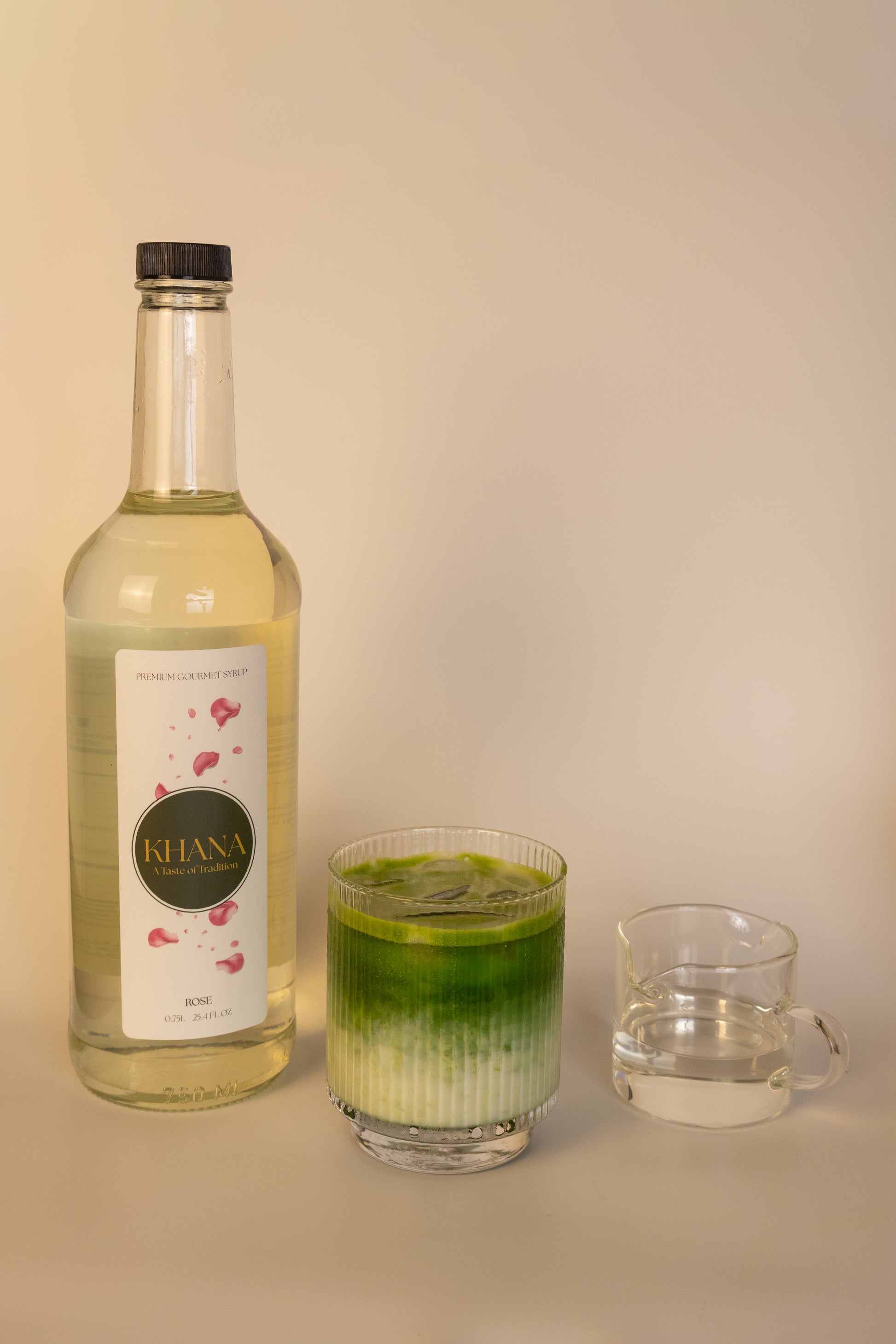Khana Rose Syrup 750mL bottle next to a glass of matcha latte and serving of syrup