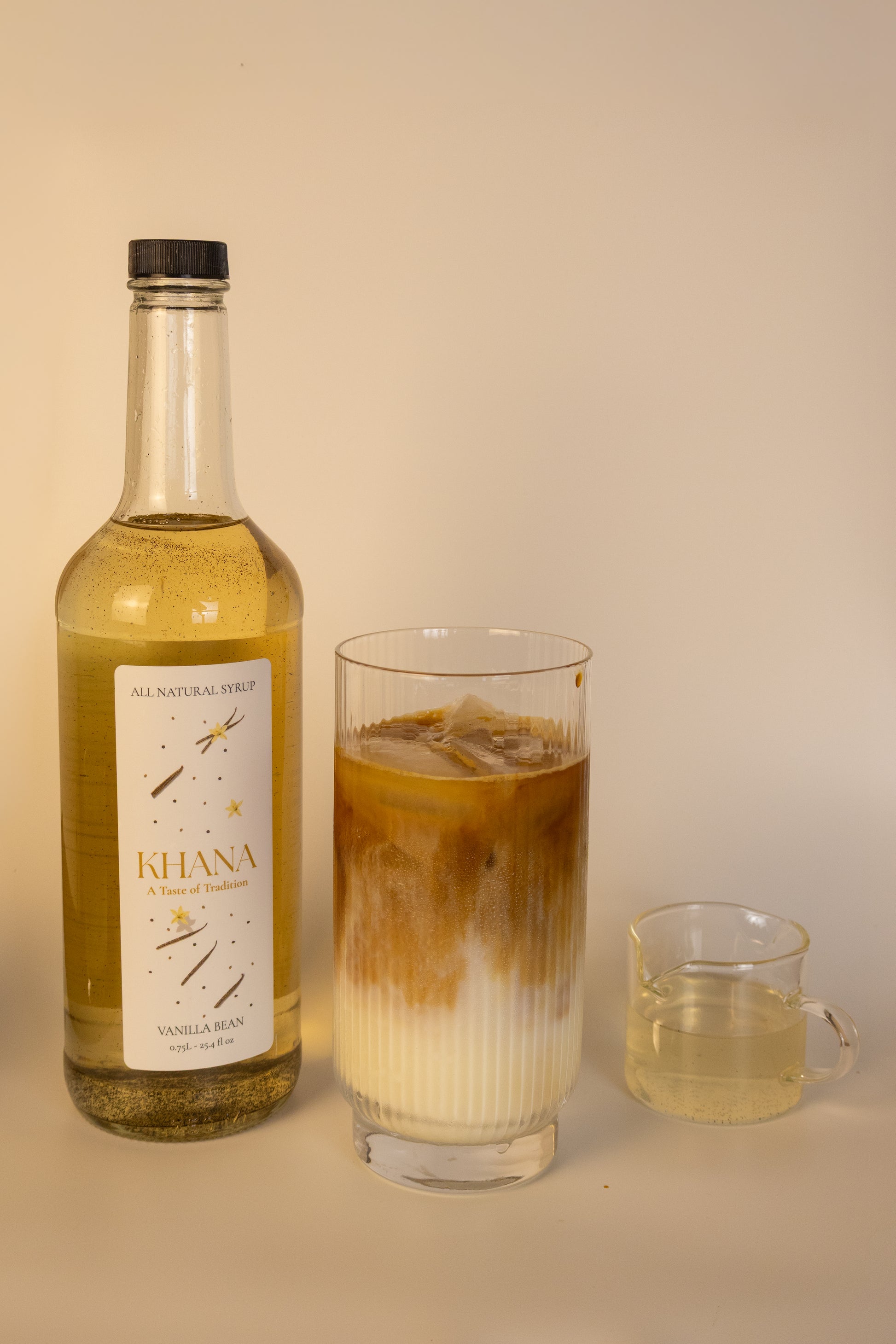 Khana Vanilla Bean 750mL Syrup with a glass of coffee latte with a serving of syrup.